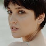 Close-up portrait of a young woman with short hair outdoors, exuding elegance.
